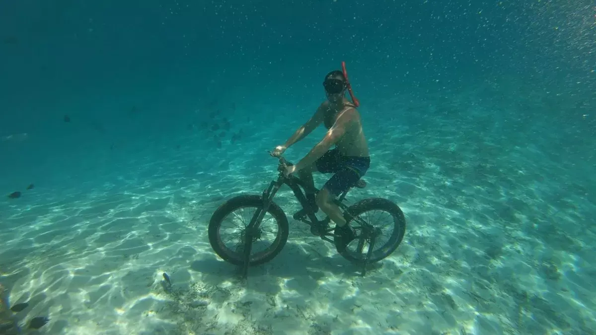 Apnéiste à vélo au fond de l’eau, sur un fond de sable clair