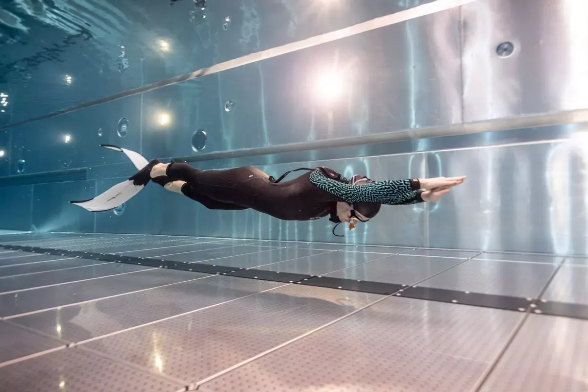 Apnéiste en dynamique avec bipalmes dans un bassin en inox